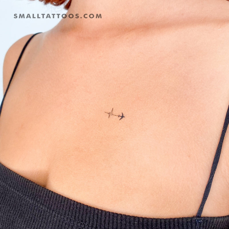 Minimalist paper airplane tattoo on the upper arm